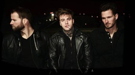 johnny in the middle with 2 of his members on either side of him in all black outfit 